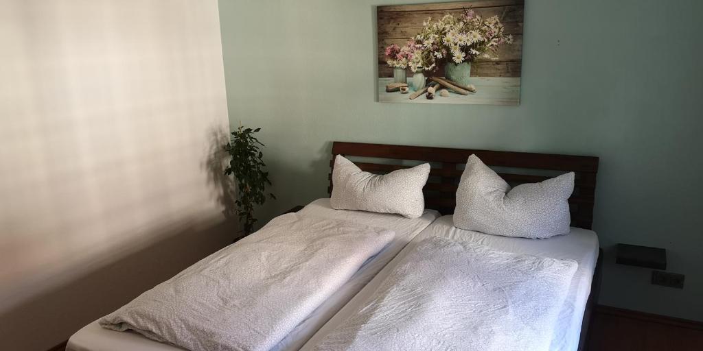 WeimarFerienwohnung/Monteurwohnung im Herzen von Ahnatal的卧室内的一张带白色床单和枕头的床