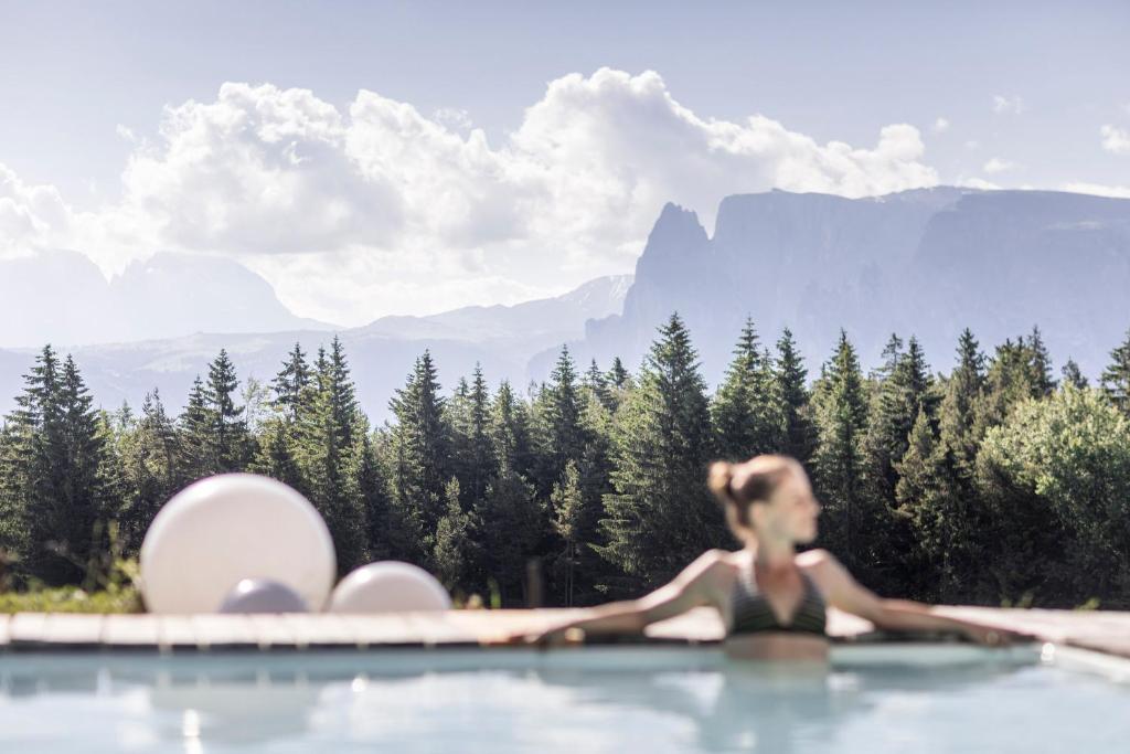 科拉尔博Hotel Tann的一位女性在一座有山背景的游泳池里