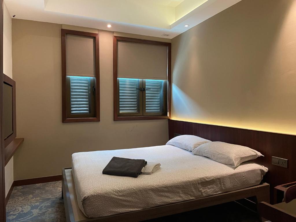 新加坡AM Hotel的一间卧室设有一张床和两个窗户。