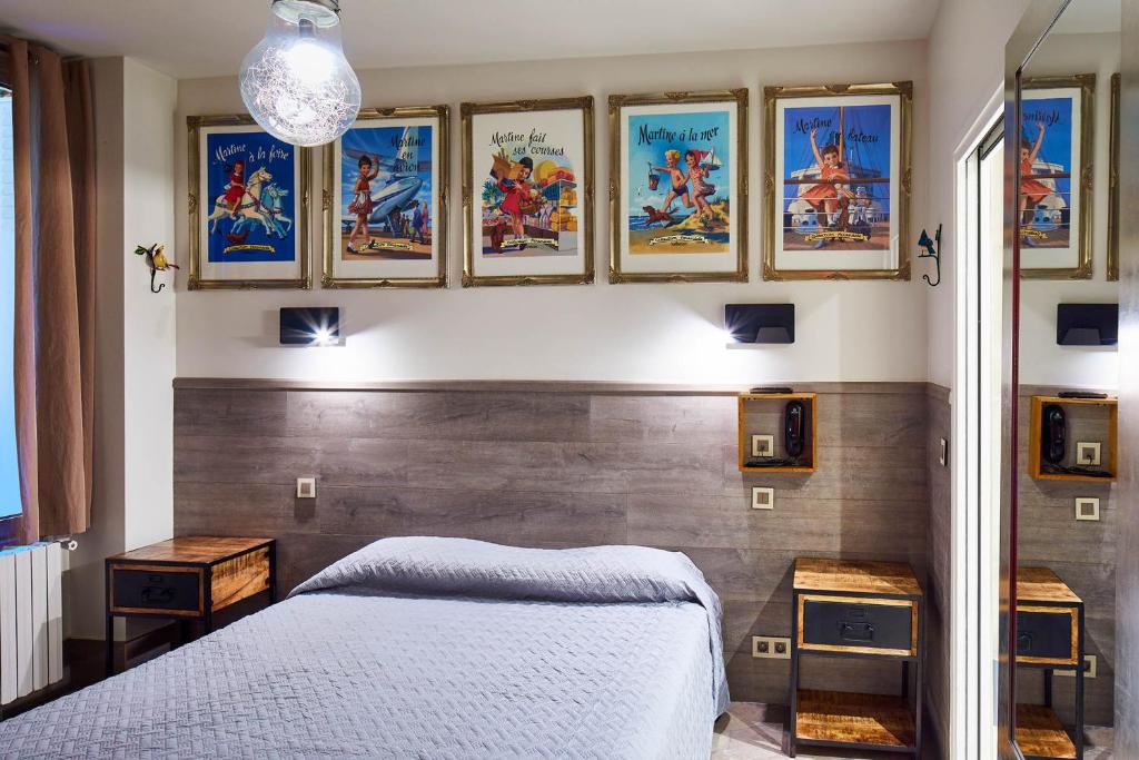 巴黎鲁贝酒店的一间卧室配有一张床,墙上挂着一些图片