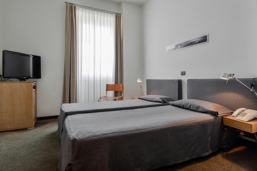的里雅斯特阿尔伯格亚拉珀斯塔酒店的酒店客房设有两张床和电视。
