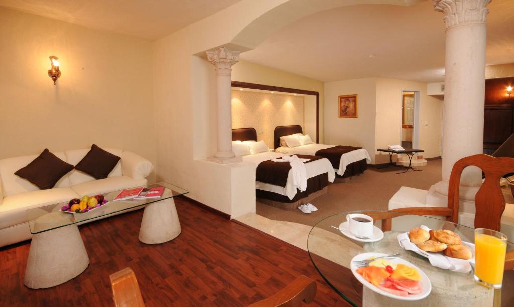 萨卡特卡斯Hotel & Spa Hacienda Baruk的客厅配有沙发和一张位于房间的床