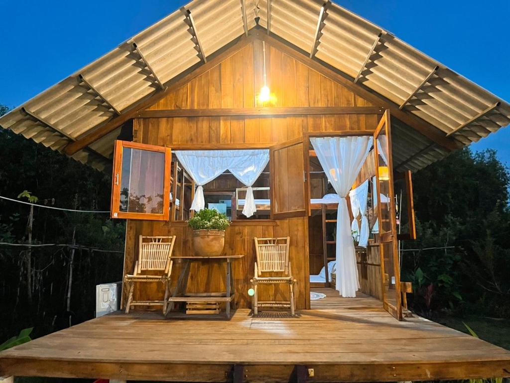 金瓯Bungalow - Farmstay Hoa Rừng U Minh的木制甲板上配有椅子的大型小木屋