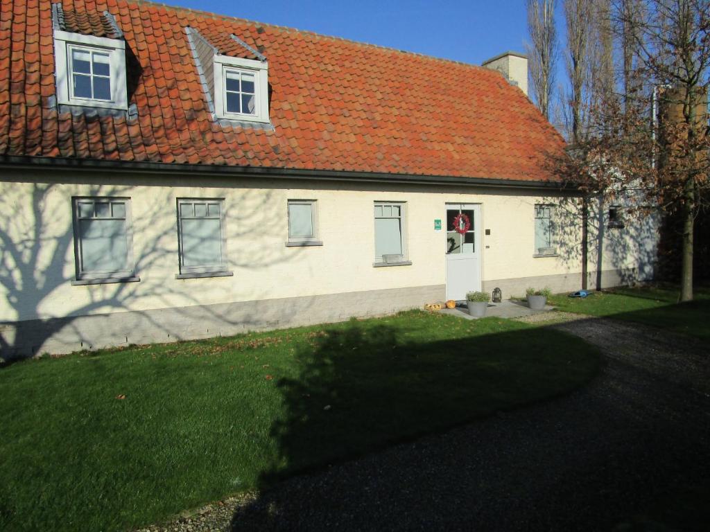 WielsbekeB&B De Pethaan的一座白色的房子,有橙色的屋顶和院子