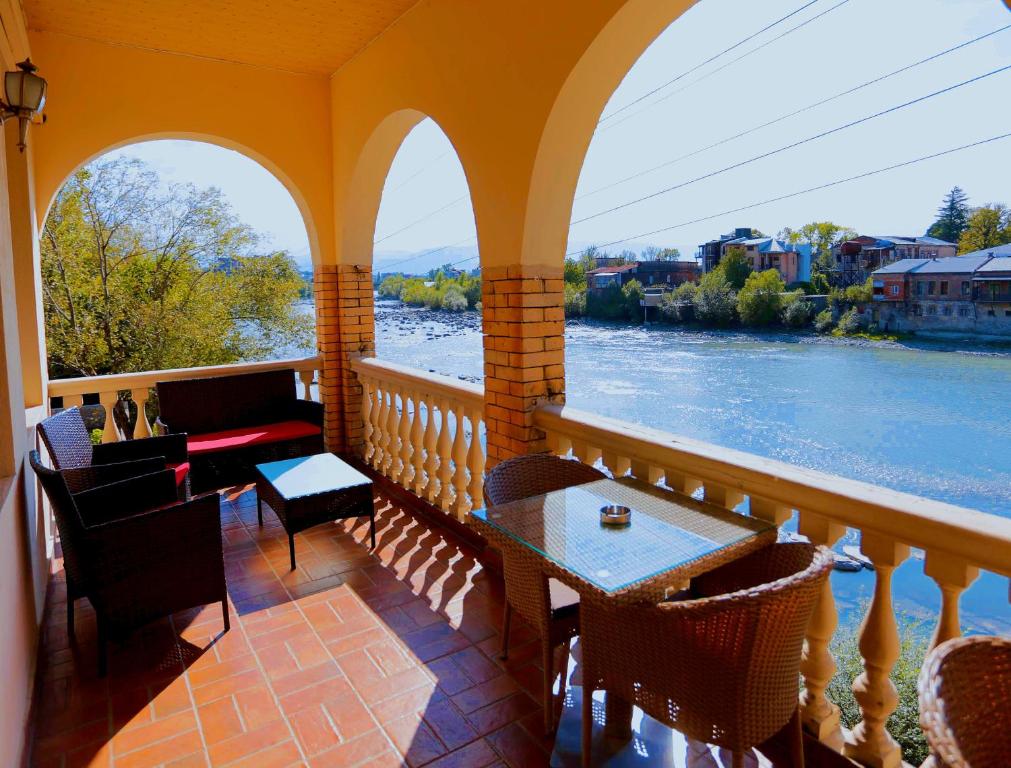 库塔伊西Sanapiro Hotel的阳台配有桌椅,享有河流美景。