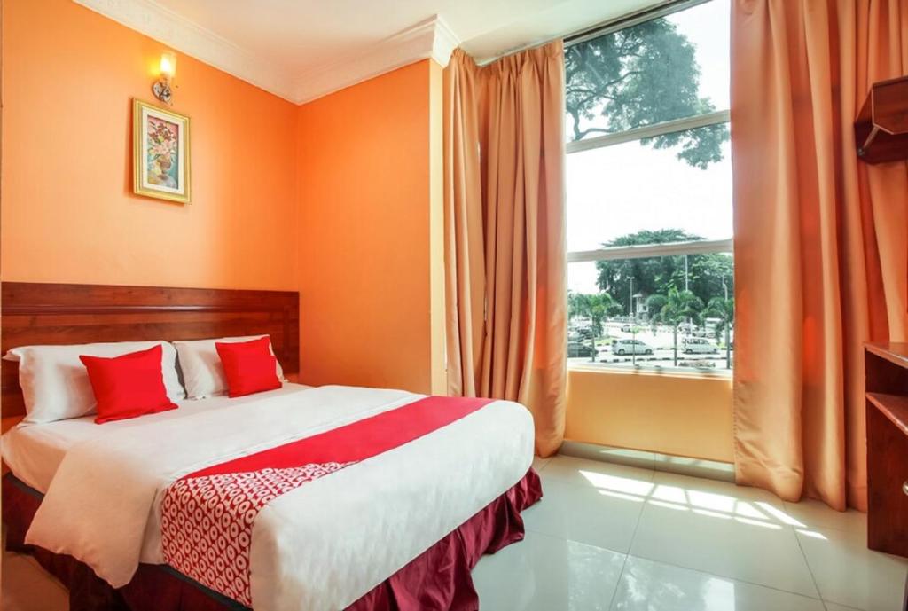 怡保My Town Hotel的一间卧室拥有橙色的墙壁,配有一张带红色枕头的床。