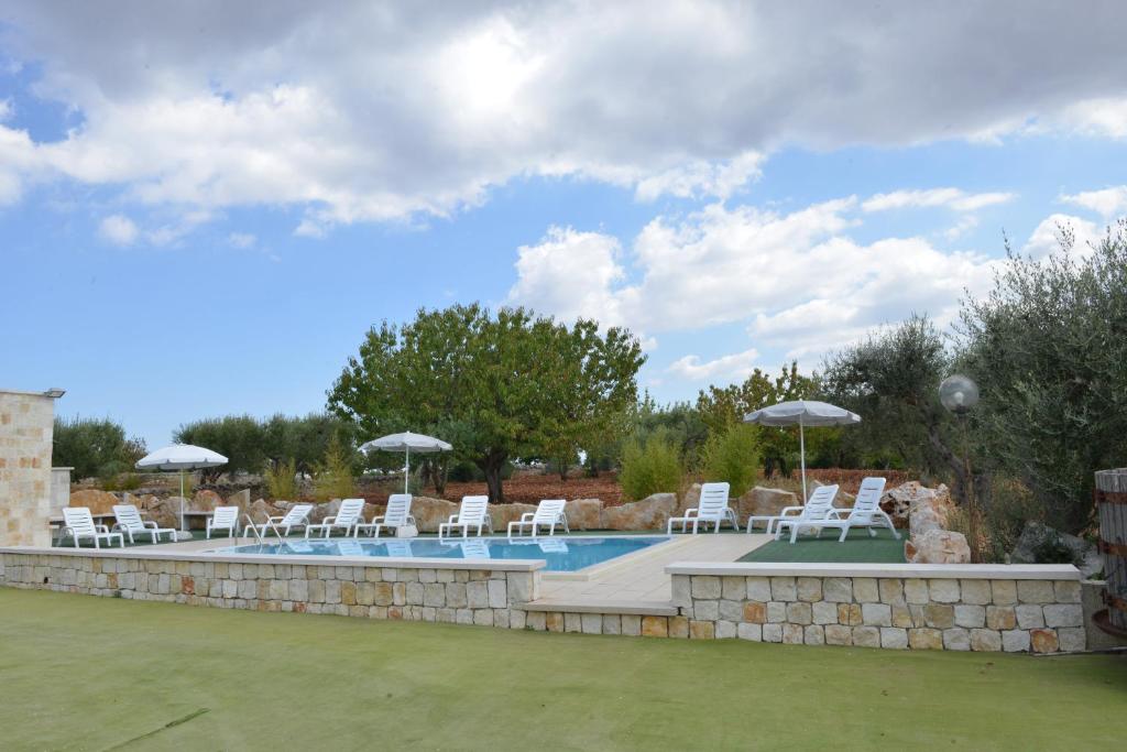 阿尔贝罗贝洛Trullo Country Relax Lumieri的一个带白色椅子和遮阳伞的游泳池