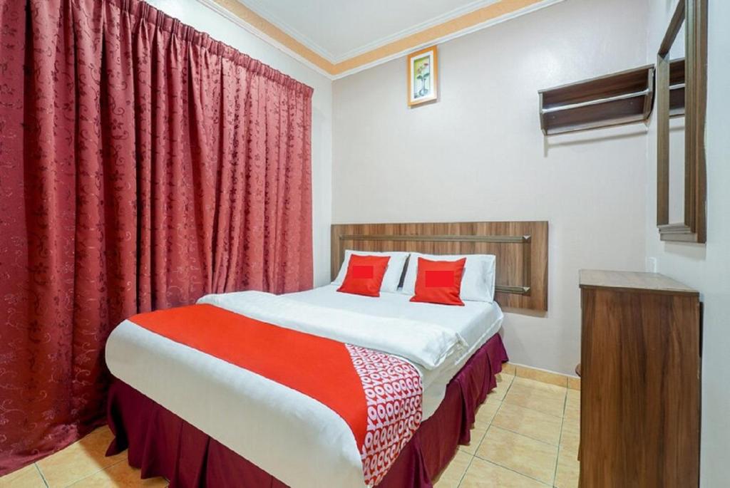 怡保Hill Times Inn Hotel的一间卧室配有一张带红色窗帘的大床