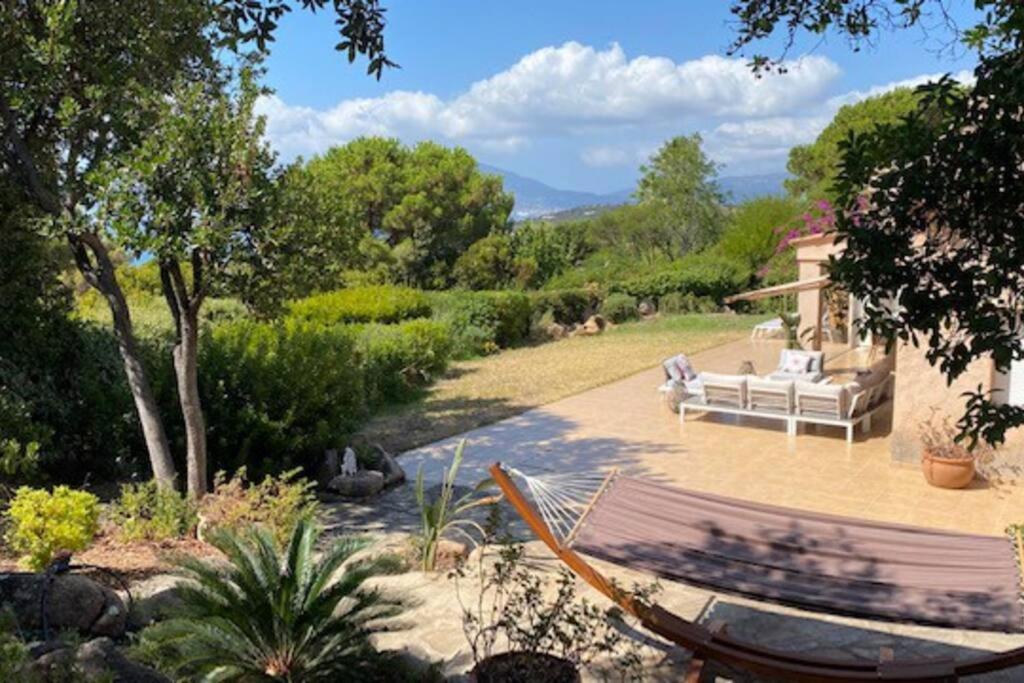 波尔蒂乔Villa 180 m2 vue Mer au calme grand terrain Porticcio的花园内设有一个带沙发和吊床的庭院。
