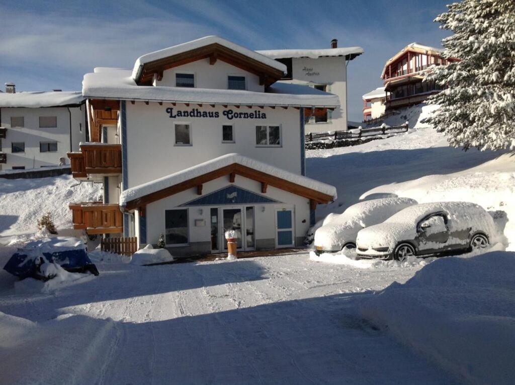 贝旺Landhaus Cornelia的两辆停在大楼前雪地里的汽车