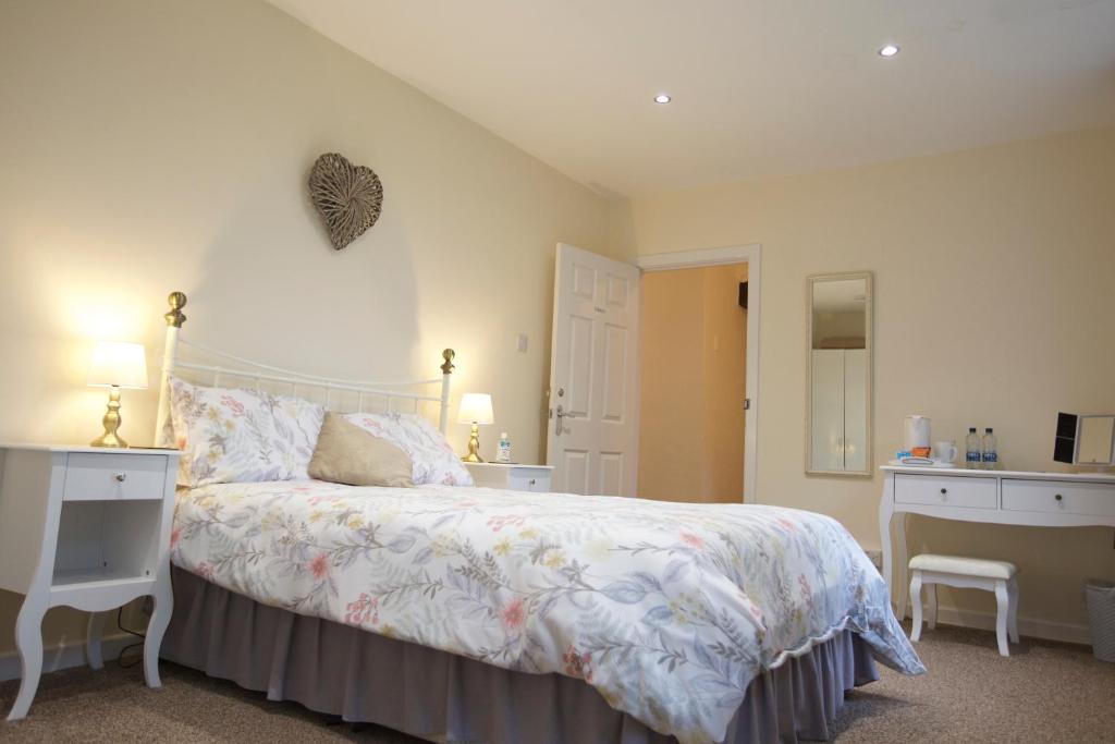 朗塞斯顿Trelaske Manor B&B的一间卧室配有一张床、一张书桌和一面镜子
