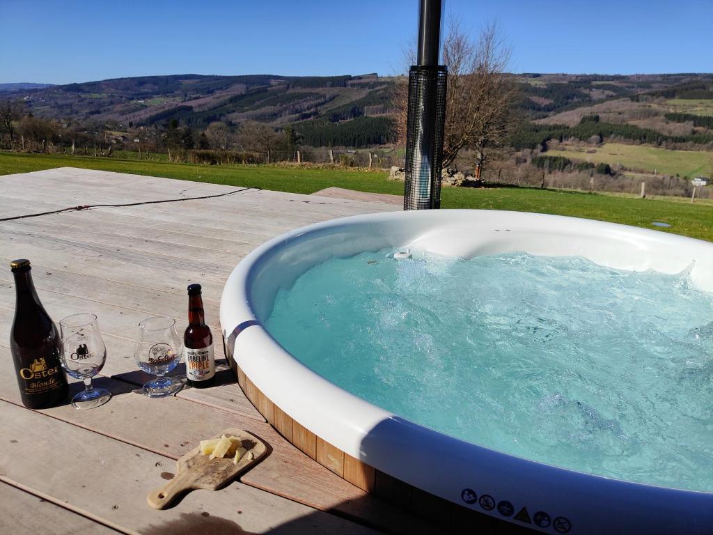 斯图蒙Le Clos des Brumes的浴缸配有2瓶葡萄酒和2杯酒