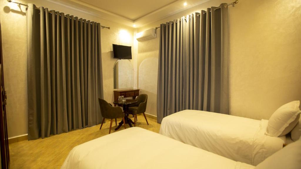 卡萨布兰卡Hotel de paris的酒店客房设有两张床和一张桌子。