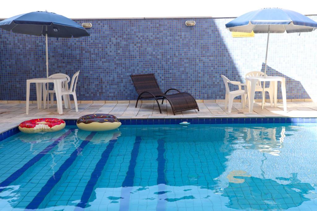 里贝朗普雷托Hotel Dan Inn Express Ribeirão Preto的游泳池配有椅子和遮阳伞以及桌椅
