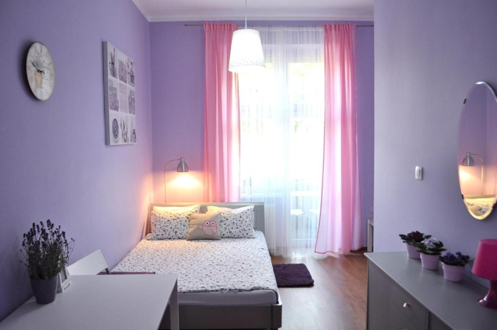 波兹南快乐之家旅馆的一间卧室配有床和一个带粉红色窗帘的窗户。