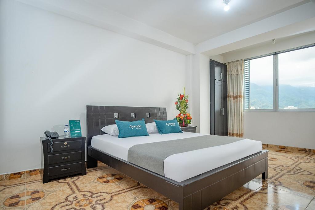 伊瓦格Ayenda Gold Plaza的一间卧室配有一张带蓝色枕头的大床