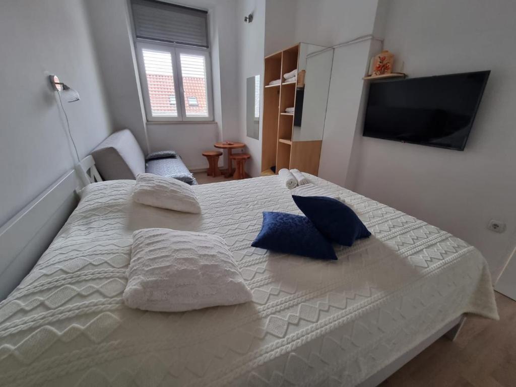 科尔丘拉Španić palace的卧室配有带蓝色枕头的大型白色床