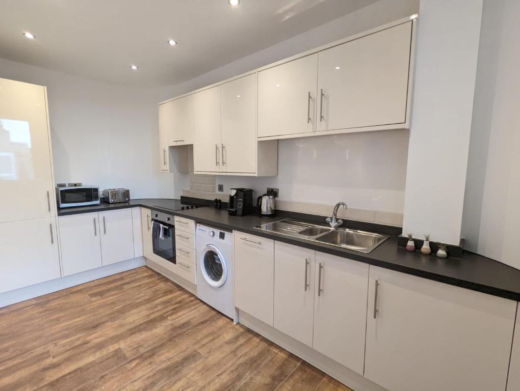 史云顿Swindon Apartments by Charles Hope的厨房配有白色橱柜、水槽和洗碗机。