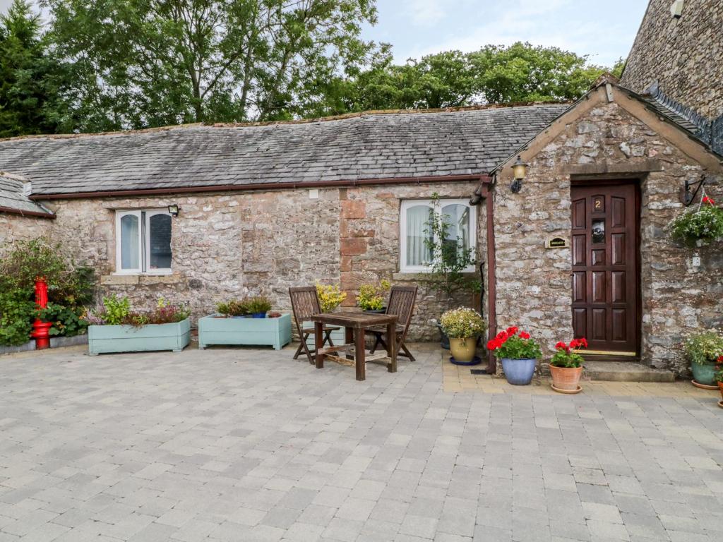 MorlandRosegarth Cottage的石头小屋前面设有桌椅
