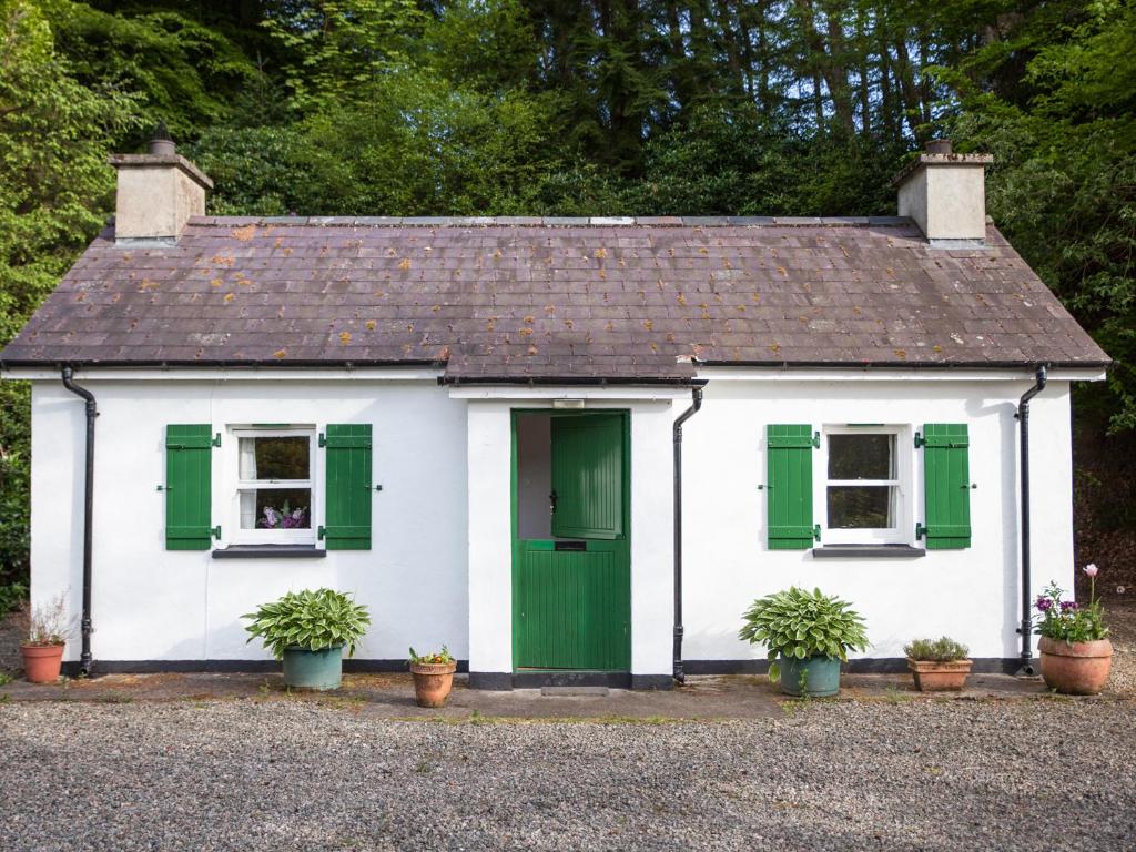 GortinMr McGregors' Cottage的白色的房子,有绿色百叶窗和盆栽植物