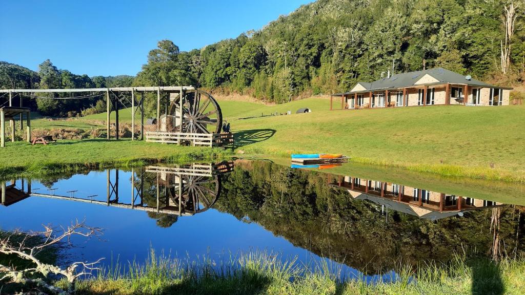 Totara FlatAhaura Lodge & Waterwheel Farm Stay的湖畔小山上的房屋