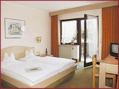 梅明根赫姆酒店的卧室配有一张白色大床和一张书桌