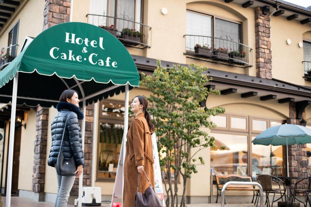 富士河口湖HOTORI no HOTEL BAN的两个女人在旅馆和蛋糕店前走