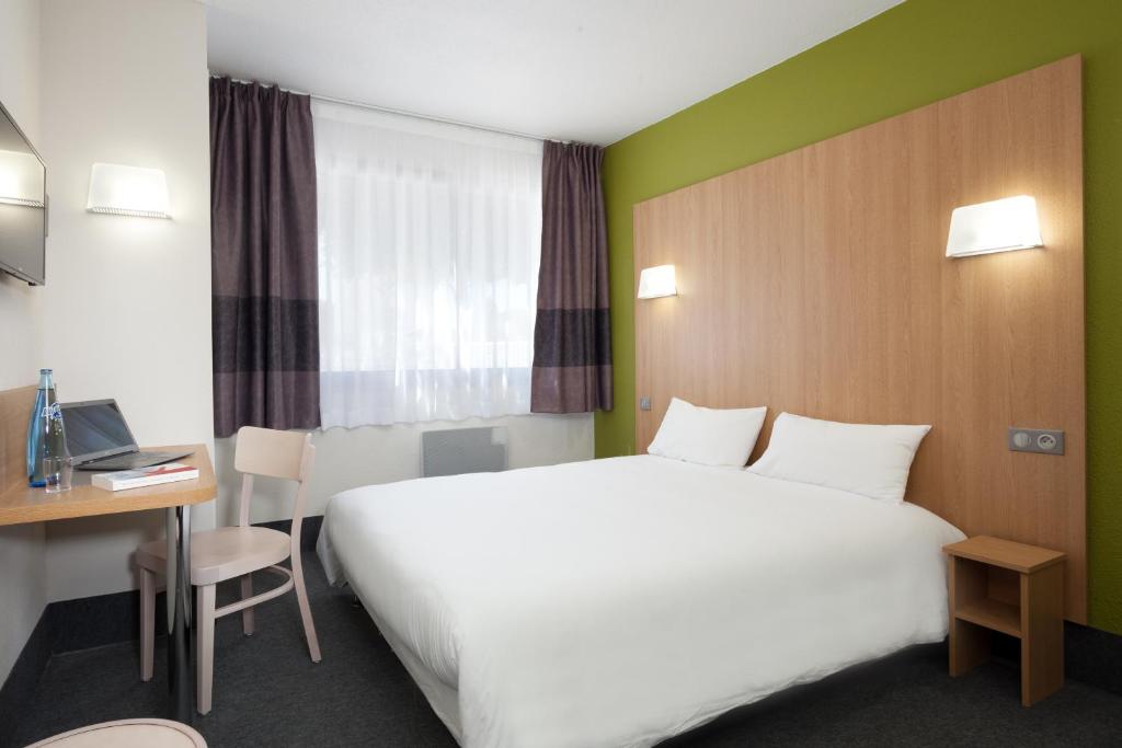 尼姆B&B HOTEL Nîmes Ville Active, parking sécurisé gratuit的酒店客房设有一张白色大床和一张书桌