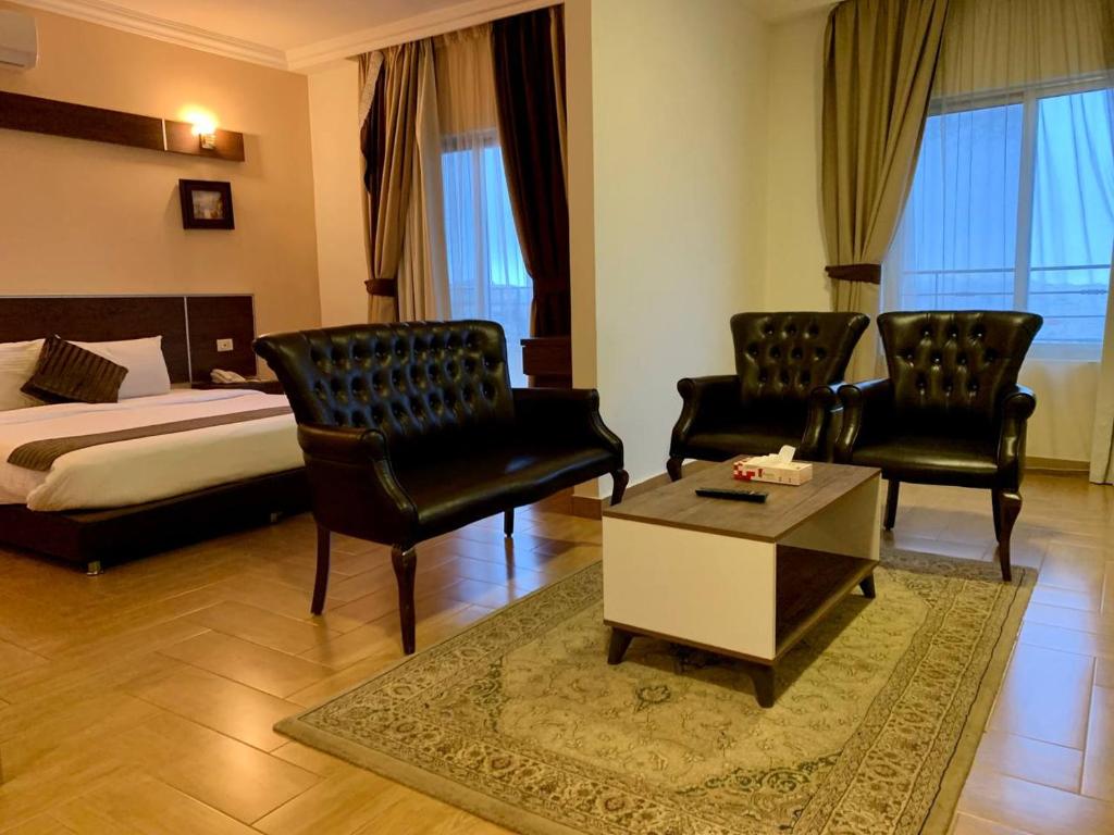 安曼Ream Hotel Amman的酒店客房配有一张床、两把椅子和一张桌子