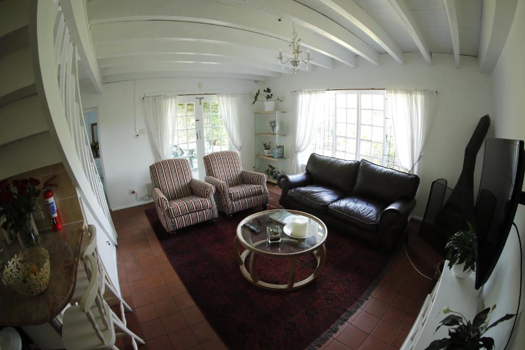 开普敦Strelitzia Cottage的客厅配有沙发、椅子和桌子