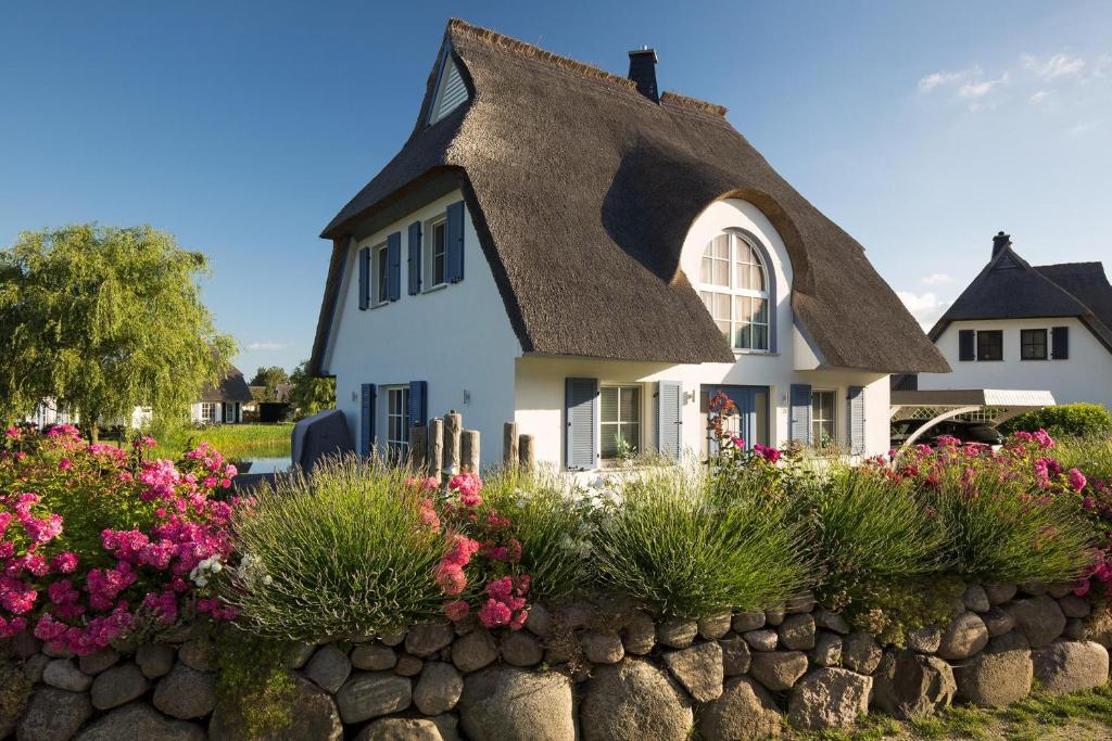 富伦多夫Ferienhaus Schilfrohrsaenger 18的白色的房子,有茅草屋顶和鲜花