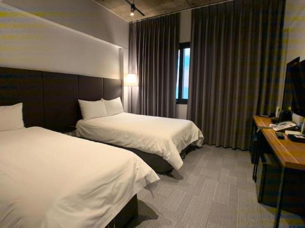 济州市Jeju Renaissance Hotel的酒店客房配有两张床和一张书桌