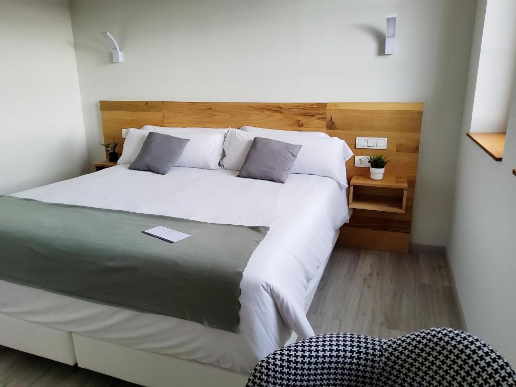 阿吉拉尔日波奥Hotel Marqués de Aguilar的卧室配有一张白色大床和一把椅子