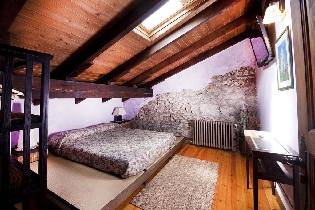PontejosPosada El Pozu La Tejera的一间带一张床的卧室,位于带木制天花板的房间内
