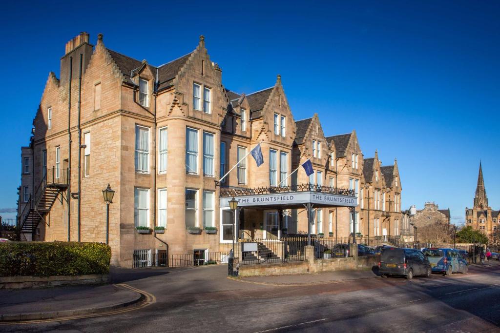 爱丁堡The Bruntsfield Hotel的一座大型砖砌建筑,前面有汽车停放