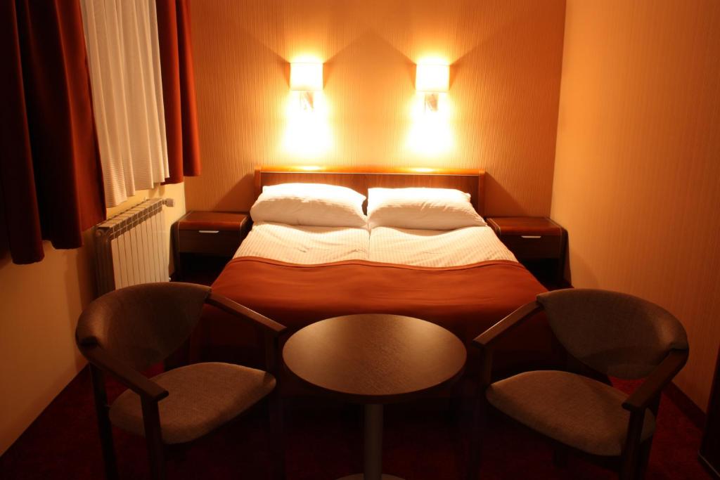 Borek Wielkopolski尹普雷斯汽车旅馆的一间小卧室,配有一张床和两把椅子