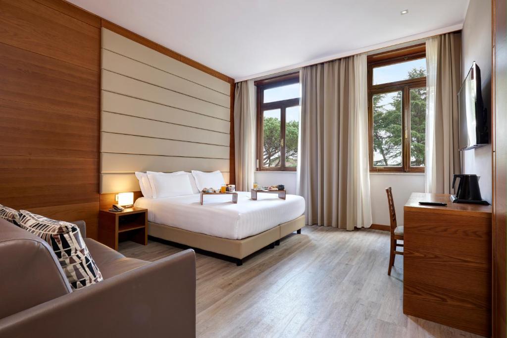 罗马西方奥里利亚酒店的一间卧室配有一张床、一张沙发和窗户。