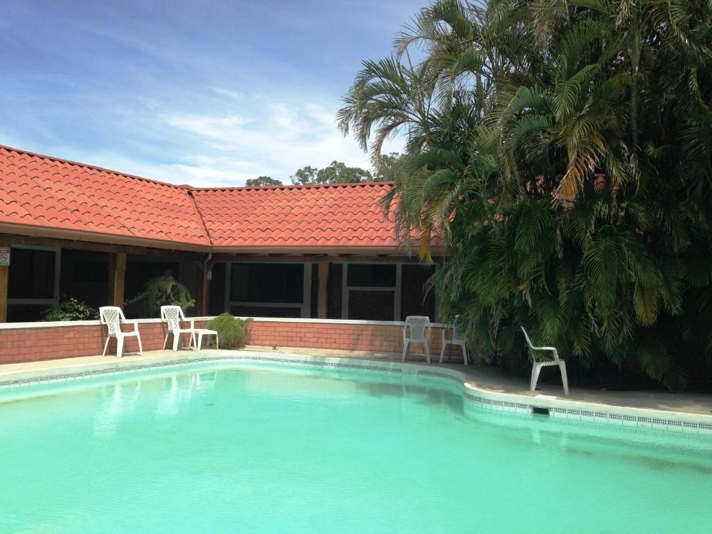 利比里亚布拉马德罗酒店的一个带两把椅子的游泳池以及一座房子