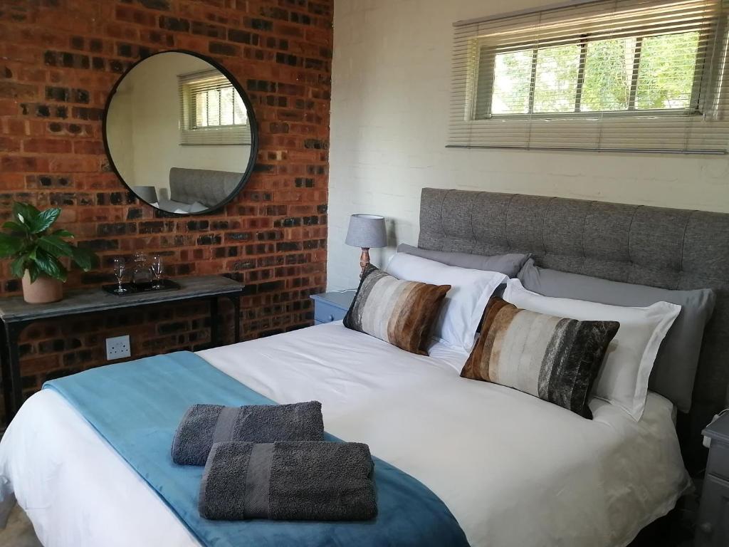 比勒陀利亚Bushbaby Cottage in Hartbeespoort的卧室配有带枕头和镜子的白色床
