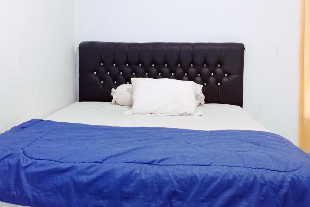 SeblatRedDoorz Syariah @ Wisma Soponyono的一张带蓝色毯子和黑色床头板的床