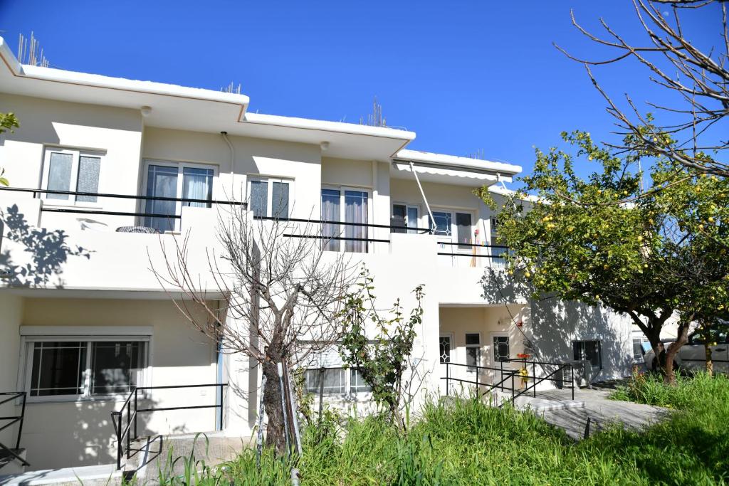 伊利索斯Iskas apartments的白色的建筑,设有黑色的阳台和树木