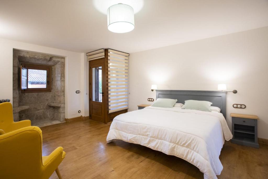 利亚内斯Casa Rural Llanes Asturias的卧室配有一张白色大床和一张黄色椅子