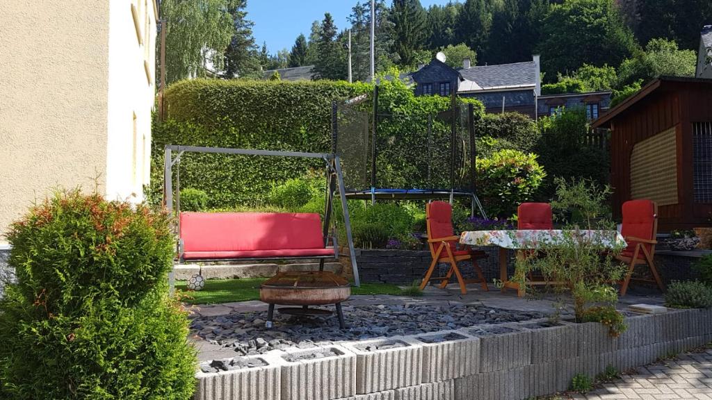 克林根塔尔Ferienwohnung mit Garten und Spielplatz的花园设有红色的沙发、椅子和桌子