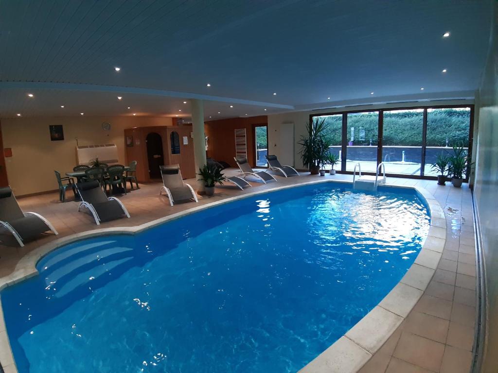 苏茨马特Les Berges de l'Ohmbach的酒店的大型游泳池配有桌椅