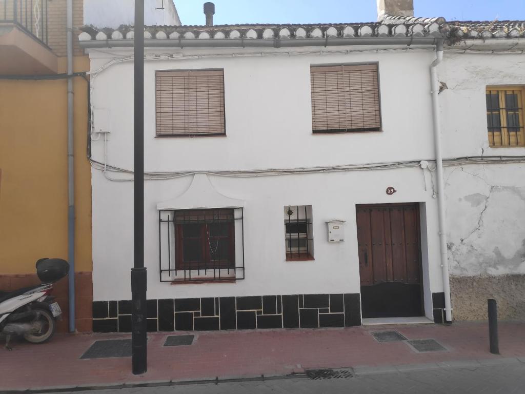 格拉纳达Casa en Purchil的一座白色的建筑,旁边设有窗户和一辆摩托车