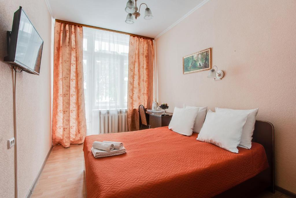 莫斯科佩瑞德尔基诺疗养酒店的一间卧室配有带橙色床单的床和窗户。
