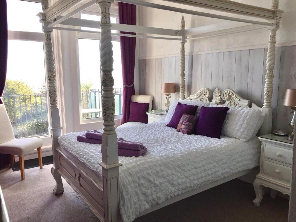 伊斯特布恩Seaview Sanctuary的一间卧室配有一张带紫色枕头的天蓬床