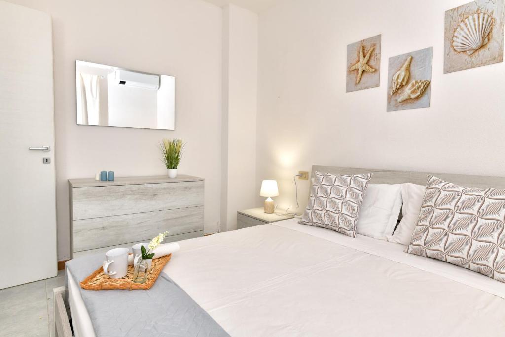 圣特奥多罗Residence Chiaro di Luna的白色的卧室设有一张大床,上面有托盘