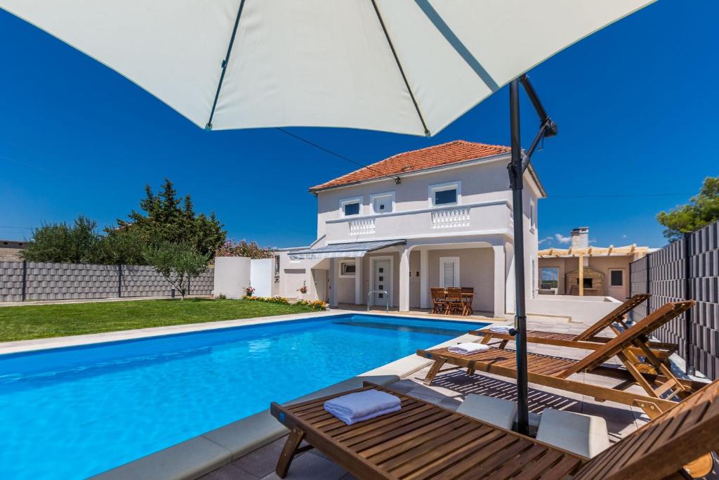 VisočaneKristina holiday home with private swimmingpool的一座带游泳池和遮阳伞的别墅