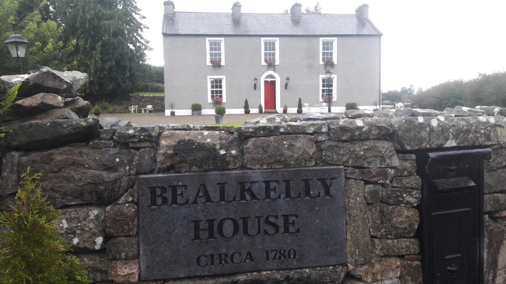 基拉卢Bealkelly Country House的前方有标志的石墙后面的白色房子